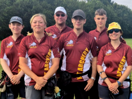 Six archers look happy having their photo taken. They're wearing deep-red Kent county uniform.