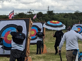 Archers pull arrows in the rain, the judge holds an umbrella which as a target face design.