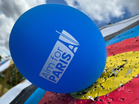 A blue 'Aim for Paris' balloon pinned to a target face