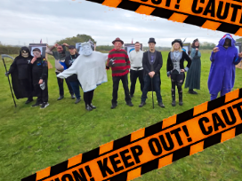 Lots of us in fancy dress, on the field of spookily decorated bosses. There are dangerous banners and spiders webs. In the crowd you will find the Grim Reaper, Freddie Kruger, the Mad Hatter and, Gengar the ghost pokemon.